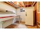 Unfinished basement with exposed ceiling, window and storage shelves at 13015 W Ohio Ave, Lakewood, CO 80228