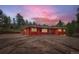 Stunning exterior of red home with inviting front yard and beautiful sunset sky in the background at 4776 Red Rock Dr, Larkspur, CO 80118