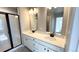 Bright bathroom with a double sink vanity, black fixtures, and a glass-enclosed shower at 2303 Peregrine Dr, Brighton, CO 80601