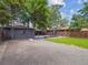 Grassy backyard with a gray-tone building, carport area, gravel landscaping, and mature trees at 3050 S Delaware St, Englewood, CO 80110