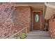 Inviting front porch with a decorative wood door and brick facade at 7140 S Reed Ct, Littleton, CO 80128