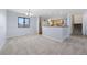 Bright living room with carpeted dining area adjacent to kitchen and staircase at 7140 S Reed Ct, Littleton, CO 80128