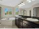 This large bathroom features dual sinks with granite countertop, tile flooring, soaking tub, and glass enclosed shower at 41 Garner Ln, Erie, CO 80516