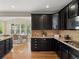 View of dining area and stylish kitchen with dark cabinetry and hardwood floors at 41 Garner Ln, Erie, CO 80516