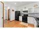 Updated kitchen boasts black appliances, white cabinetry, and hardwood floors at 11705 W Stanford Ln, Morrison, CO 80465
