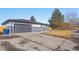 View of home's side yard and gray garage with modern-look door at 8217 W 71St Pl, Arvada, CO 80004