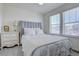 A relaxing bedroom with large windows, soft neutral walls, soft carpeting, and a comfy bed with a gray headboard at 8760 Ginkgo Loop, Parker, CO 80134