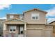 Two-story home featuring a two-car garage and a stone and beige horizontal siding exterior at 887 Sundance Ln, Erie, CO 80516