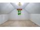 Bright attic space featuring a ceiling light fixture and a single window, with neutral carpeting at 2535 S Julian St, Denver, CO 80219