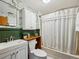 Updated bathroom with white fixtures, green beadboard, and leafy patterned wallpaper at 2733 S Riverview Dr, Idledale, CO 80453