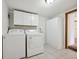 Bright laundry room with white washer, dryer, cabinets, and tiled floor at 2733 S Riverview Dr, Idledale, CO 80453