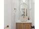 Modern half bath with a round vessel sink atop a wood vanity and a stylish arch mirror at 2844 Quitman St, Denver, CO 80212
