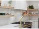 Bright kitchen featuring open shelving, a decorative backsplash, and a stainless steel range with gold knobs at 2844 Quitman St, Denver, CO 80212