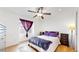 Bright bedroom features a ceiling fan, hardwood floors, and a large window with dark purple curtains at 3071 S Truckee St, Aurora, CO 80013