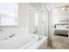 Bathroom featuring a soaking tub with shower, glass enclosure, and bright natural light at 8953 E Northfield Blvd, Denver, CO 80238