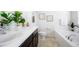 Well-lit bathroom with double vanity, tile floors, and a separate soaking tub at 8953 E Northfield Blvd, Denver, CO 80238