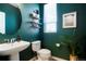 Chic half bathroom featuring dark green walls, modern fixtures, and decorative shelving at 8953 E Northfield Blvd, Denver, CO 80238