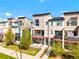 Aerial view of modern townhomes with balconies, manicured lawns, and streetscape under a blue sky at 8953 E Northfield Blvd, Denver, CO 80238