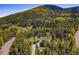 Picturesque aerial view of the home surrounded by a dense forest, with a hill covered in autumn colors in the background at 32252 Steven Way, Conifer, CO 80433