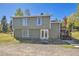 Back of home with white framed double doors, a small patio and stairs going to the deck at 32252 Steven Way, Conifer, CO 80433