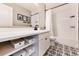 Stylish bathroom featuring patterned floors, white cabinets, and a shower with white tile surround at 795 Woodmoor Acres Dr, Monument, CO 80132