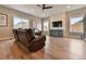Spacious living room features a ceiling fan, wood floors, large windows, and a decorative fireplace wall with mounted television at 795 Woodmoor Acres Dr, Monument, CO 80132