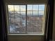 Bright window view showcasing the neighborhood homes and snow-covered street, framed by neutral curtains at 6847 S Webster St # A, Littleton, CO 80128