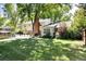 Spacious backyard with a lush lawn, patio, and mature trees providing ample shade at 6624 S Sycamore St, Littleton, CO 80120