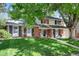 Charming two-story home with a brick facade, a well-manicured lawn, and mature trees in a suburban setting at 6624 S Sycamore St, Littleton, CO 80120