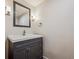 Powder room with a black vanity, white sink, and decorative wall sconces at 1843 S Pierson Ct, Lakewood, CO 80232