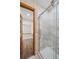 Bathroom with a glass shower featuring gray and white marble patterned tiles and a wooden door in the background at 1843 S Pierson Ct, Lakewood, CO 80232