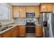 Close-up of a kitchen area featuring a granite countertop, wooden cabinetry, and stainless steel appliances at 1843 S Pierson Ct, Lakewood, CO 80232