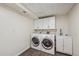 Bright laundry room featuring a washer, dryer, utility sink, and white cabinets for ample storage space at 1843 S Pierson Ct, Lakewood, CO 80232