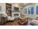 Inviting living room featuring a stone fireplace, built-in bookshelves, and hardwood floors, creating a cozy ambiance at 3242 Waterfront Dr, Monument, CO 80132