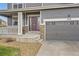 Close up of front entrance with gray garage door and front porch with white railings and concrete steps at 14110 Greenfield Loop, Parker, CO 80134