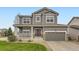 Charming gray two-story home featuring a welcoming front porch and well-manicured lawn and a two car garage at 14110 Greenfield Loop, Parker, CO 80134
