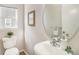 Bright powder room featuring a round mirror, pedestal sink, and white toilet at 1838 Wilson Cir, Erie, CO 80516
