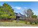 Backyard view of a two-story home with a deck, lush greenery, and mature trees at 2130 Frontier Ln, Franktown, CO 80116