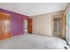 Bedroom with access to bathroom and balcony through doorways with a colorful purple accent wall at 2130 Frontier Ln, Franktown, CO 80116