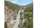 Stunning aerial view of a property nestled in a serene valley with lush greenery and a winding stream at 4364 Colorado 103, Idaho Springs, CO 80452