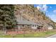 Quaint stone cottage featuring a covered entrance and a scenic mountain backdrop with mature trees at 4364 Colorado 103, Idaho Springs, CO 80452