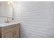 Chic bathroom features a wood vanity with gold fixtures, an arched mirror, and a stylish white brick accent wall at 1060 S Parker Rd # 36, Denver, CO 80231