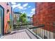 Inviting outdoor patio space with wooden decking and metal railings, offering views of surrounding buildings at 2565 Champa St, Denver, CO 80205