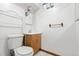 Compact bathroom featuring a toilet, wooden vanity, sink, mirror, and towel rack at 7140 Avrum Dr, Denver, CO 80221