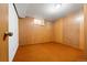 Empty room with orange carpet, wood walls, one window, and one door at 7140 Avrum Dr, Denver, CO 80221