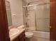 Bathroom with a white sink, a wooden vanity, and a tub with sliding glass doors at 812 S Ouray St, Aurora, CO 80017