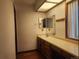 Well-lit bathroom vanity featuring an extended countertop, a large mirror and wooden cabinets at 812 S Ouray St, Aurora, CO 80017