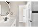 Modern bathroom featuring a sleek vanity, round mirror, and white subway tile with a dark accent stripe at 8080 E Dartmouth Ave # 26, Denver, CO 80231