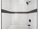 Tiled shower featuring white subway tile with a dark accent stripe, complemented by a black shower head fixture at 8080 E Dartmouth Ave # 26, Denver, CO 80231