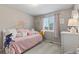This bedroom is charming with soft pink accents, plush pillows, and a sunlit window for a cozy and peaceful atmosphere at 5426 Bobcat St, Frederick, CO 80504